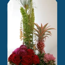 Tall tropical floral arrangement with red roses and a pineapple