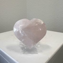 Pale pink heart-shaped crystal on a clear stand