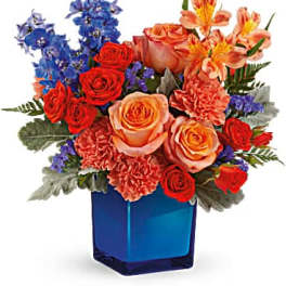 Bouquet of red and peach roses with blue flowers in a blue vase