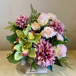 Arrangement of pink roses, green orchids, and pink dahlias in a wooden box.