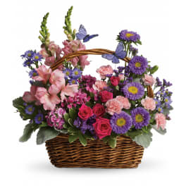 Basket arrangement of pink and purple flowers with butterfly picks