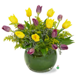 Yellow and purple tulips arranged in a round glass vase