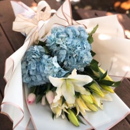 Blue hydrangeas and white lilies wrapped in white paper