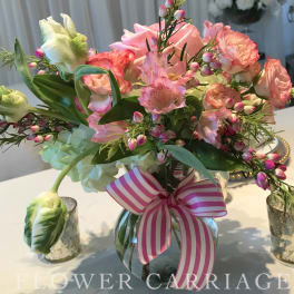 Pink and peach bouquet in a glass vase with a striped ribbon