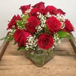 Red roses arranged in a low glass vase with baby's breath