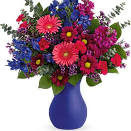 Colorful mixed bouquet in a blue vase with pink, blue, and purple flowers