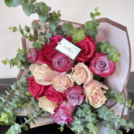 Bouquet of pink and lavender roses with eucalyptus in brown wrap