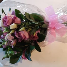 Bouquet of pink and white flowers wrapped in clear plastic with a pink bow