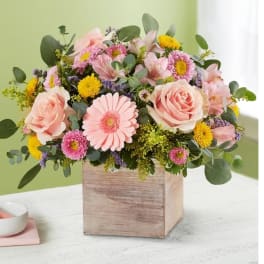 Pink and yellow mixed flower arrangement in a wooden box