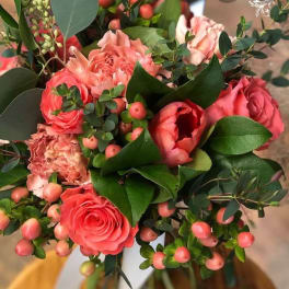 Coral roses and pink carnations in a bouquet with berry accents