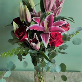 Bouquet of pink lilies and red roses in a clear glass vase