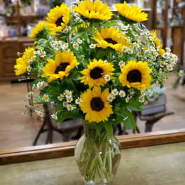 Bouquet of yellow sunflowers and small white daisies in a clear glass vase