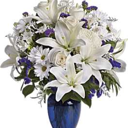 White lilies and daisies arranged in a blue vase