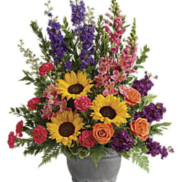 Mixed bouquet with sunflowers, roses, and purple spikes in a gray vase