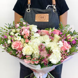 Large bouquet of pink and white roses with hydrangeas held by a florist