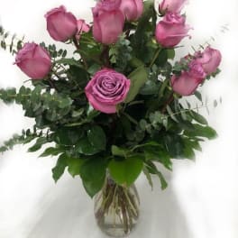 Pink roses arranged in a clear glass vase with greenery