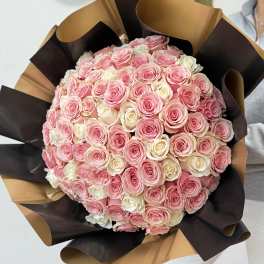 Large bouquet of pink and white roses wrapped in brown and black paper