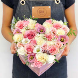 Heart-shaped box filled with pink and cream roses and other blooms