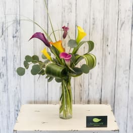 Tall bouquet of colorful calla lilies in a glass vase
