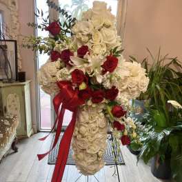 Tall standing floral arrangement of white and red roses with a red ribbon