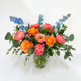 Bright mixed bouquet of pink and orange flowers in a clear glass vase