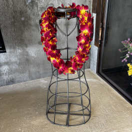 Red and yellow orchid lei draped over a black metal stand