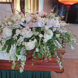 Large white floral spray on a wooden casket