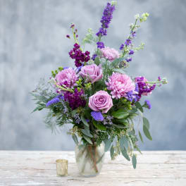Lavender roses and purple flowers in a glass vase