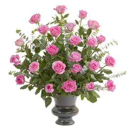 Pink roses arranged in a dark vase with airy greenery