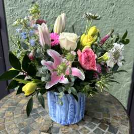 Colorful mix of lilies, roses, tulips and other blooms in a blue ceramic vase