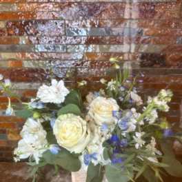 Bouquet of white roses and blue-white flowers in a wooden box
