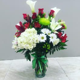 Bouquet of red roses, white lilies, and white daisies in a glass vase