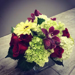 Bouquet of red roses, pale hydrangeas, and purple orchids with a yellow daisy