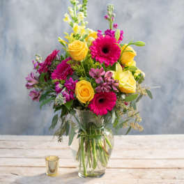 Bouquet of yellow roses and pink gerbera daisies in a glass vase