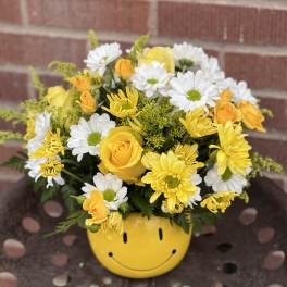 Yellow and white bouquet in a smiley-face pot