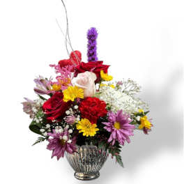 Mixed bouquet of roses, daisies, and carnations in a glass vase