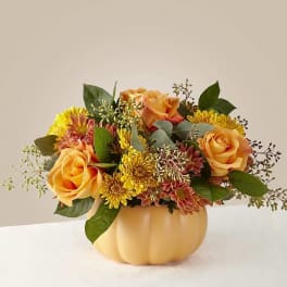 Orange roses and yellow mums in a pumpkin-shaped vase
