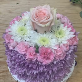 Pink rose and chrysanthemum arrangement on a round white base