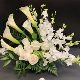White calla lilies, roses, and orchids arranged in a low bouquet