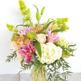 Mixed bouquet of pink lilies, cream roses, and white hydrangea in a glass vase
