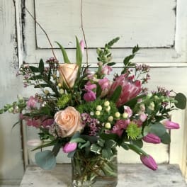 Mixed bouquet in a clear glass vase with pink and peach blooms