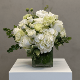 White floral arrangement in a square glass vase