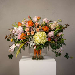 Mixed bouquet in a clear glass vase with orange, pink, and cream blooms