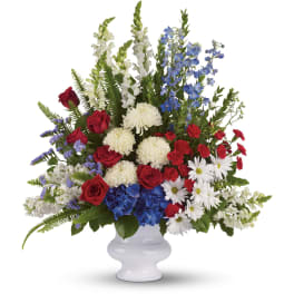 Tall red, white, and blue flower arrangement in a white pedestal vase