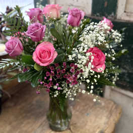Pink and lavender roses arranged in a glass vase with white baby's breath