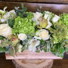 Low floral centerpiece with white roses, green hydrangeas, and succulents in a wooden box