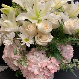White lilies and cream roses in a vase with pink hydrangeas