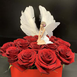 Red roses in a red box with a small fairy figurine and white wings