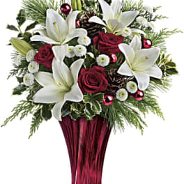 White lilies and red roses in a red glass vase with holiday accents