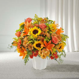 Orange and yellow mixed flower arrangement in a white vase
